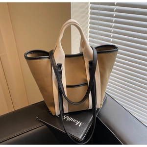 Detail of khaki canvas tote bag with black leather trim and detachable shoulder strap
