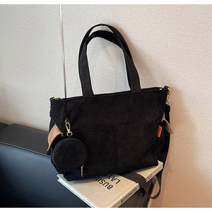 Detail of black corduroy tote bag showing side pouch and wide shoulder strap