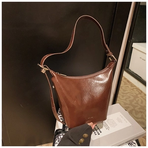 Detailed macro view of the shiny brown oil-wax leather bucket bag with zipper closure