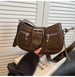 Detail shot of vintage dark brown faux leather shoulder bag with metallic zipper pockets