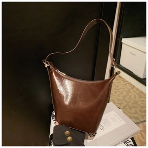 Detailed close-up of a vintage brown oil-waxed leather hobo bucket bag with high-gloss finish