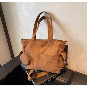 Detail of brown corduroy tote bag with side flap pocket and round coin purse pendant