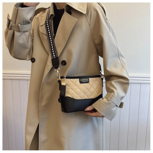 Detail of quilted leather bucket bag with contrast stitching and woven shoulder strap