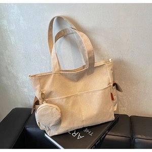 Detail of beige corduroy tote bag featuring a front pocket and detachable round coin purse