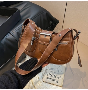 Detail view of vintage brown leather bag with metallic buckles and multi-pocket design