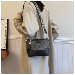 Detail of grey quilted bucket bag with wide geometric strap worn by model