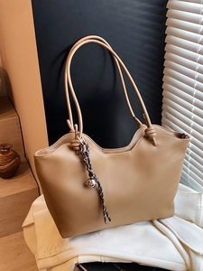 Minimalist khaki leather tote bag with unique wavy top and decorative bell charm