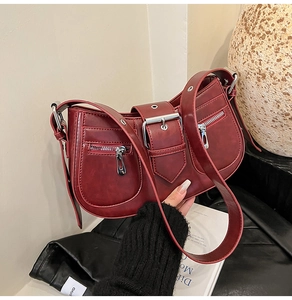 Detail of dark red vintage shoulder bag with silver hardware and utility pockets
