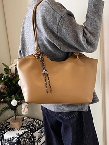Minimalist large leather tote bag in camel with woven pendant shown on model shoulder