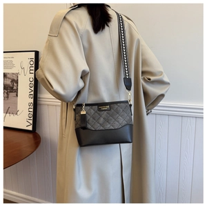 Detail view of grey quilted crossbody bag with black leather base and woven strap
