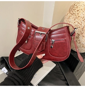 Macro shot of burgundy faux leather texture and silver buckle on Y2K shoulder bag