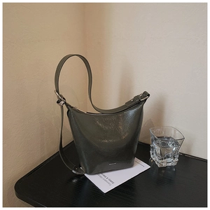 Detail of dark olive green bucket bag with wrinkled patent leather and NO FILTER text