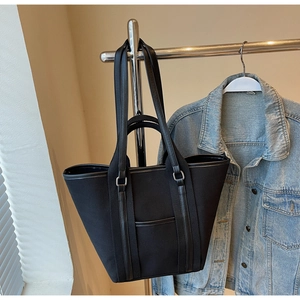 Close-up of black canvas tote bag with leather trim and dual handles for daily commute