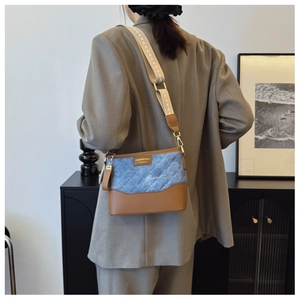 Detail of blue denim and brown leather quilted crossbody bag with stylish woven strap