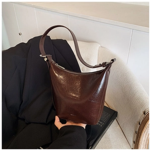Detailed shot of dark brown glossy leather shoulder bag with sleek metallic zipper