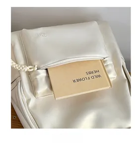 Detailed shot of the cream leather backpack front pocket and embossed Hoog brand logo