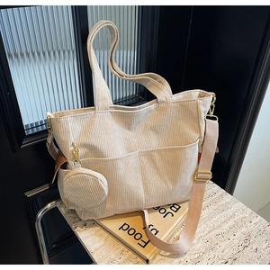 Close-up of beige corduroy tote bag with adjustable strap and small round coin purse