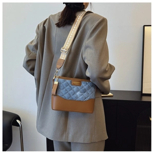 Close-up of quilted denim and brown leather bucket bag with stylish woven shoulder strap