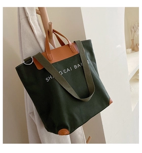 Macro shot of dark green canvas tote bag with brown leather handles and sturdy strap