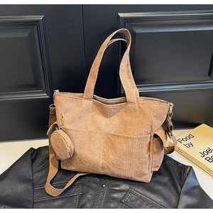 Close-up of brown corduroy tote bag with small round coin purse on black leather