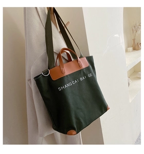Detail view of large canvas tote bag with brown leather handles and brand logo print