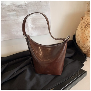 Close-up of glossy brown faux leather underarm bucket bag with rich oil wax finish