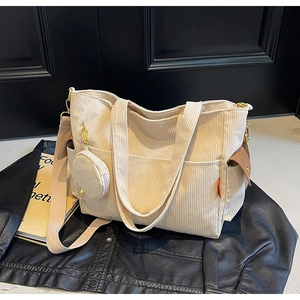 Detail of beige corduroy tote with side pockets, wide strap and small round coin purse