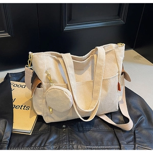Detail of cream corduroy tote bag with small round pouch on a black leather jacket