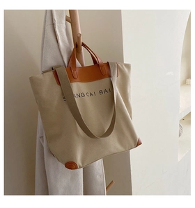 Detail of canvas tote bag showing reinforced leather corners and black printed text