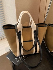 Large khaki canvas tote bag with black leather trim and dual handles for women