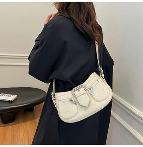 Detail of cream shoulder bag with metallic buckle and silver zippers in Y2K style