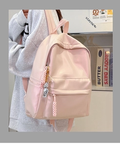 Detail of light pink backpack showing the Hoog logo and silver robot charm decoration