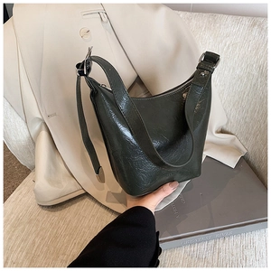 Detail of dark green oil-wax leather bucket bag with silver hardware and wide strap