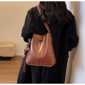 Detailed side view of vintage brown leather bucket bag with a cute rabbit plush charm