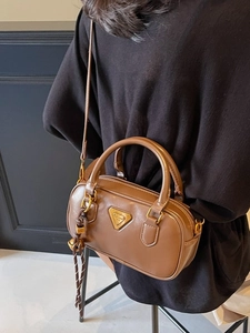 Brown PU leather crossbody bag with top handle and gold logo on indoor model