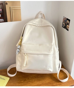 Detail of cream white leather backpack featuring Hoog logo and silver bear charm pendant