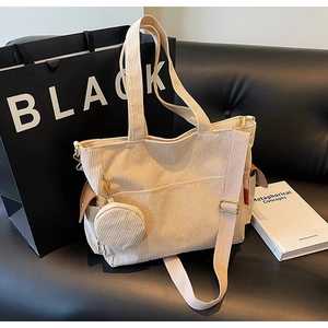 Detail of beige corduroy tote bag with adjustable strap and small round coin purse