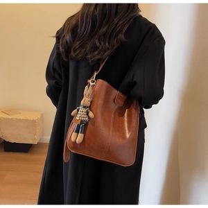Detailed view of vintage brown leather bucket bag featuring a cute rabbit charm accessory