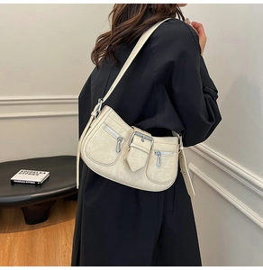 Macro detail of the creamy white retro shoulder bag showing metallic zipper and buckle
