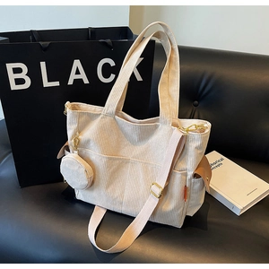 Detailed texture of cream corduroy tote bag with adjustable strap and small coin purse