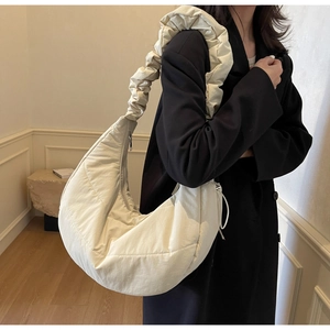 Detail of quilted beige crescent bag with puffy cloud strap on black blazer