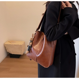 Close-up of vintage brown leather bucket bag featuring a cute bunny plush charm
