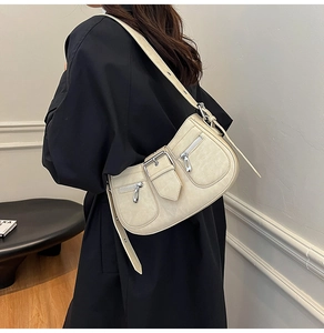 Side view of cream-colored faux leather shoulder bag with buckle and zipper details