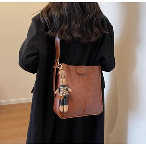 Brown vintage leather bucket bag featuring a cute rabbit charm and metal clasp closure