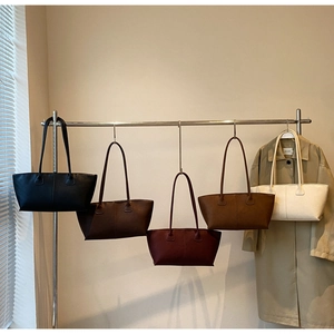 Row of minimalist tote bags in five colors hanging on a metal rack for display