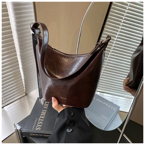 Detail of dark brown vintage oil wax leather shoulder bag with metallic buckle and logo