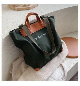 Detail of forest green canvas tote bag with leather handles and HANG CAI BAI print
