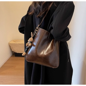 Close-up of vintage dark brown bucket bag with smooth oil finish and rabbit charm