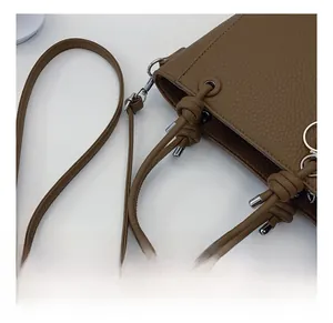 Detail showing brown lychee pattern leather bucket bag with knotted handle and silver hardware