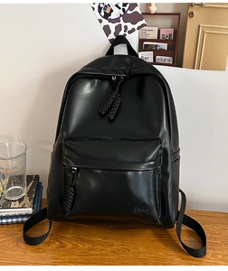 Close-up of minimalist black leather backpack with woven zipper and embossed logo